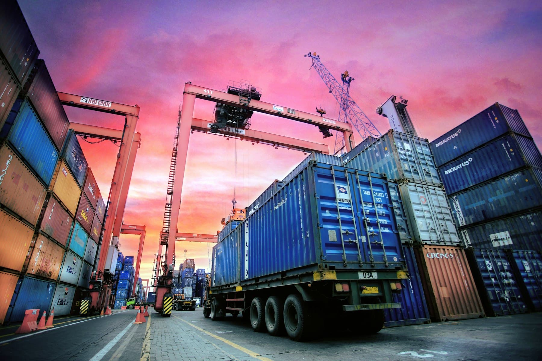 Un camion carica un container in un porto al tramonto